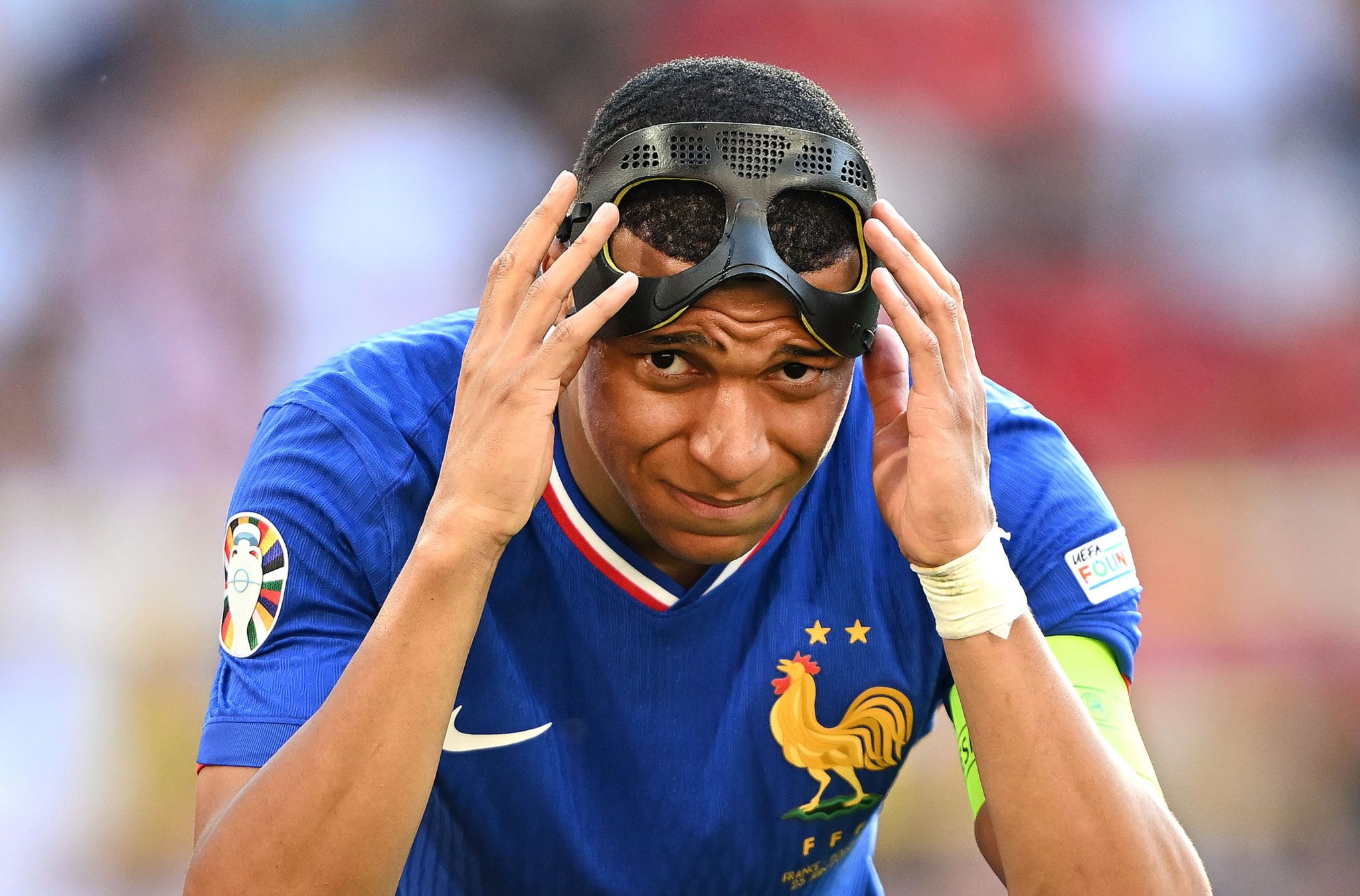 Kylian Mbappe lifts a mask to protect a nose injury during France's 1-1 group-stage draw with Poland