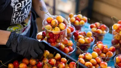 Getty Images A worker arranges Rainier cherries at a fruit stand in the Pike Place Market in Seattle, Washington, US, on Thursday, July 4, 2024. 