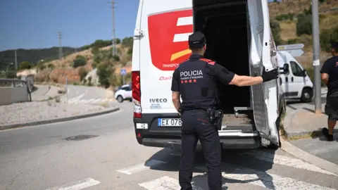 Reuters A police officer checks a vehicle at a roadblock set up to find Mr Puigdemont